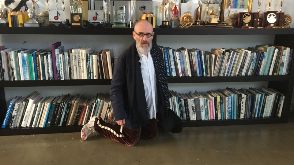 Director Tony Kaye beside a shelf of film awards and books